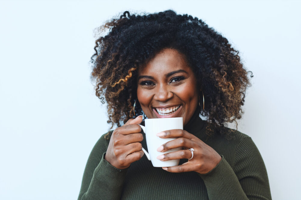 Playful personal branding photo of a woman smiling behind a coffee cup, showcasing authenticity and personality