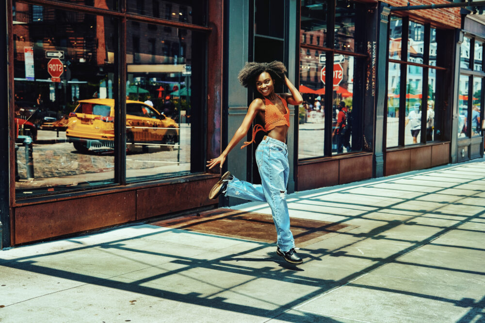 Smiling female dancer jumping mid-air in NYC’s Meatpacking District during urban personal branding shoot